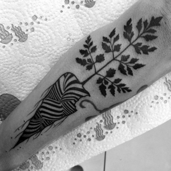 Bold black ink carrot tattoo with abstract striped detailing and delicate leafy tops, blending geometric and organic elements for a unique design.
