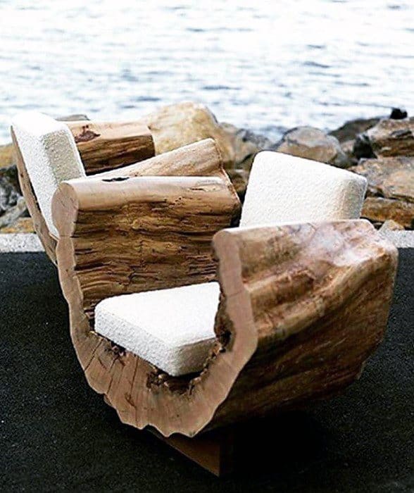 Carved wood chairs with curved natural frames and white cushioned seating by the water.