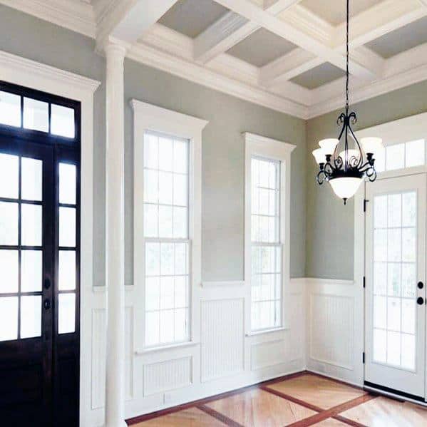 Bright entryway with large windows, chair rail, and a dark wood door, featuring a decorative ceiling light