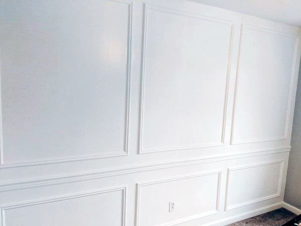 White paneled wall with decorative molding, a chair rail, and a power outlet at the bottom