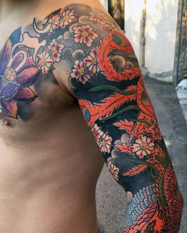 Vibrant full sleeve tattoo featuring cherry blossoms, a bold phoenix, and intricate floral details for a striking Japanese-inspired design