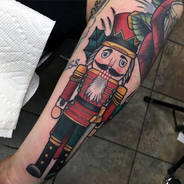 Christmas tattoo of a classic nutcracker soldier in a red and gold uniform, featuring bold outlines, holly leaves, and festive details for a traditional holiday look.