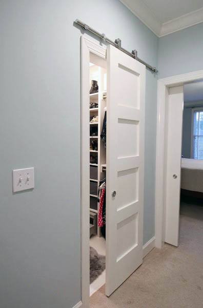 Sliding door opens to reveal a spacious closet with shelves and clothes in a light blue room