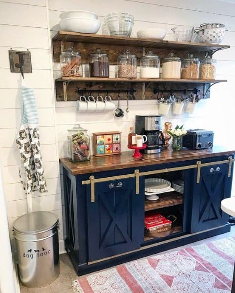 Navy blue coffee bar with sliding doors, rustic shelves, glass jars, and a shiplap wall.