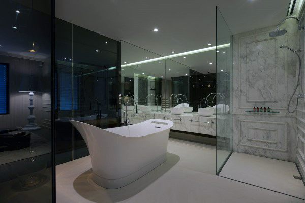 Contemporary bathroom with freestanding tub, glass walls, and large wall-to-wall mirror.
