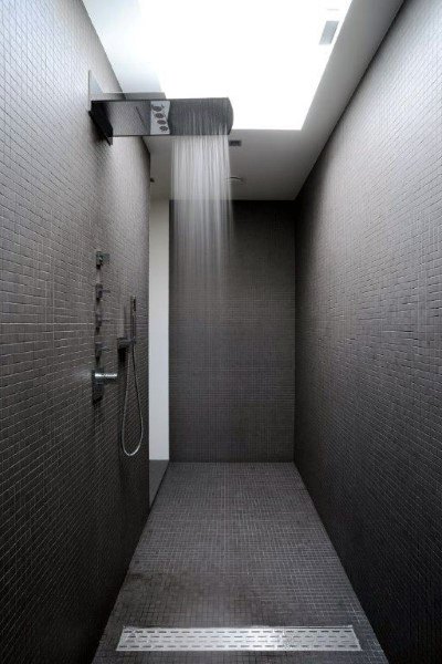 Modern bathroom with dark tiles and a large, luxurious rain shower overhead