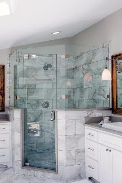 Modern corner bathroom with glass shower enclosure, marble tiles, and white cabinets