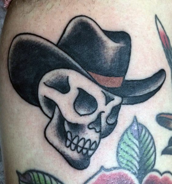 Black and gray tattoo of a cowboy skull wearing a wide-brimmed hat with a brown band, done in a bold traditional style with strong outlines and shading.