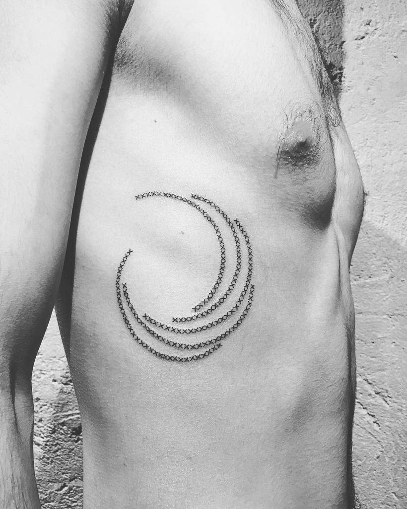 Minimalist cross-stitch tattoo of curved, wave-like lines, designed to resemble embroidered stitches in a flowing pattern