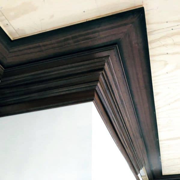 Unique dark brown stained wood crown molding with intricate detailing, adding a luxurious touch to the room's architecture