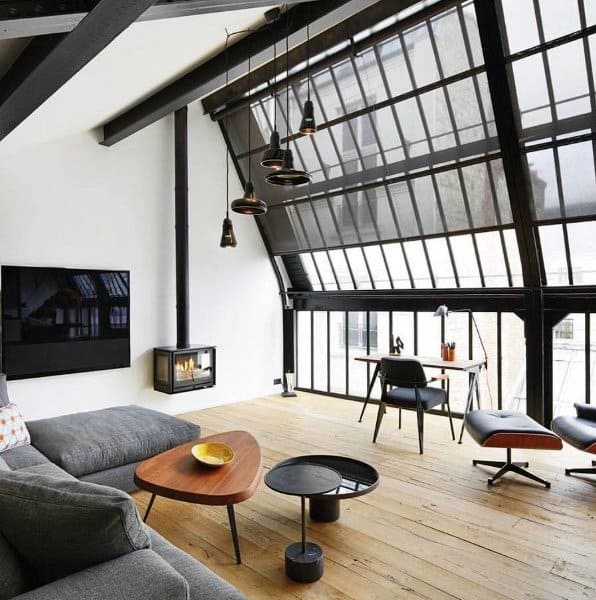 Modern industrial loft with slanted glass walls, a cozy fireplace, and minimalist wooden furniture.