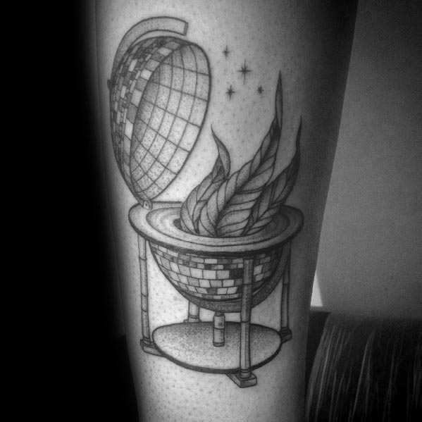 Black and grey tattoo of a disco ball designed as a globe, opening to reveal flames inside, blending retro and surreal elements in a bold design.