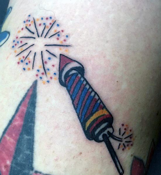 Tattoo of a colorful striped firework rocket with lit sparks and bursting fireworks, designed in a bold traditional style with vibrant details.
