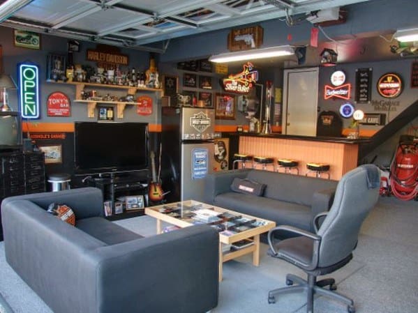 Garage man cave with sofas, TV, neon signs, sports memorabilia, and a bar area