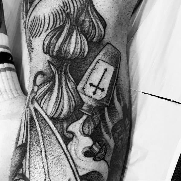 Black and grey garlic tattoo with bold shading, fine details, and gothic elements, creating a dark and artistic botanical design.