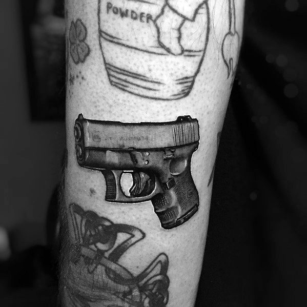 Realistic black and grey tattoo of a compact Glock pistol on the forearm, featuring detailed shading and depth for a bold and three-dimensional effect.