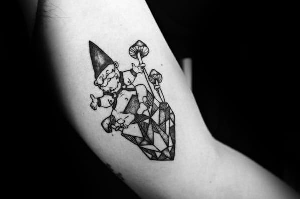 Black and white tattoo of a playful gnome sitting on a faceted crystal, holding a mushroom and making a hand gesture, blending fantasy with geometric elements.