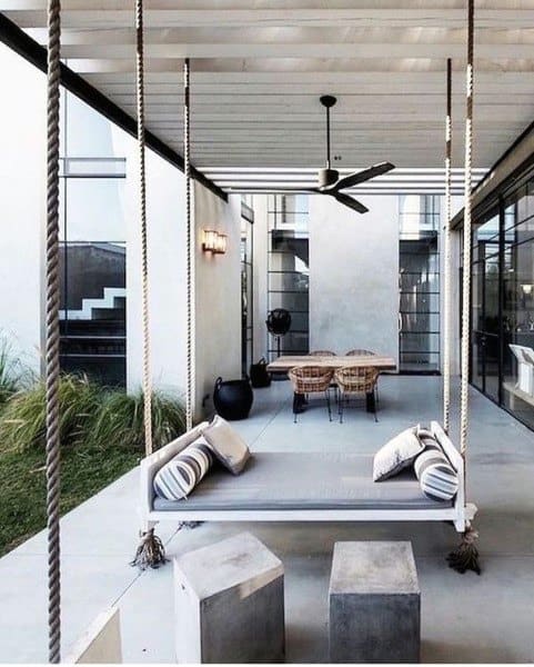 Modern hanging daybed with rope supports, striped cushions, and a sleek patio setting.