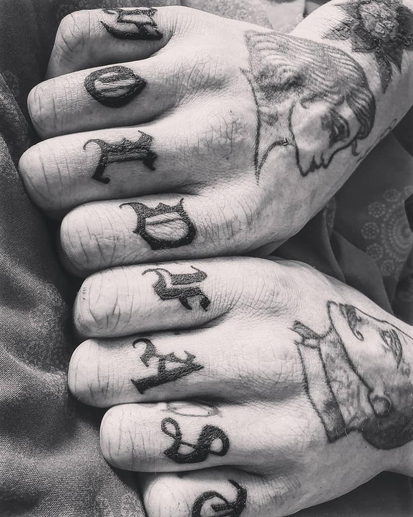 Black and white tattooed hands with "HOLD FAST" on knuckles