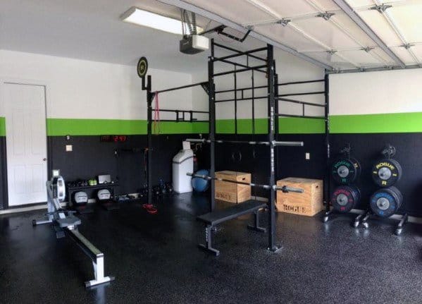 Garage gym with rubber flooring, pull-up bars, rowing machine, wooden boxes, and weight plates.