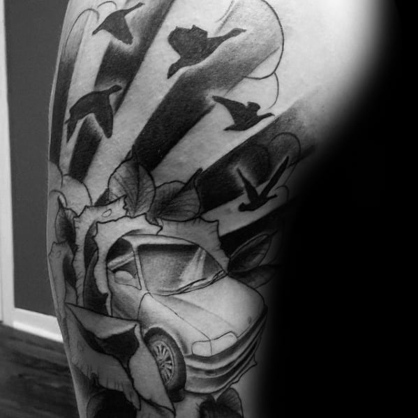 Black and gray Honda Civic tattoo on a man's arm, featuring a dynamic design with birds, sun rays, and a breaking-through effect.