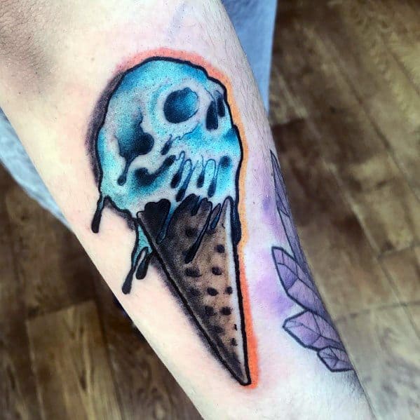Tattoo of a melting blue skull-shaped ice cream scoop on a waffle cone, featuring bold shading, drips, and an orange glow for a striking contrast.