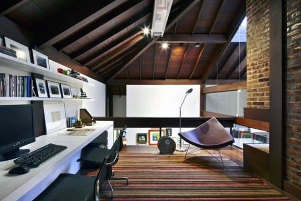 Rustic home office with vaulted wooden ceiling, white desk, and vibrant striped rug.