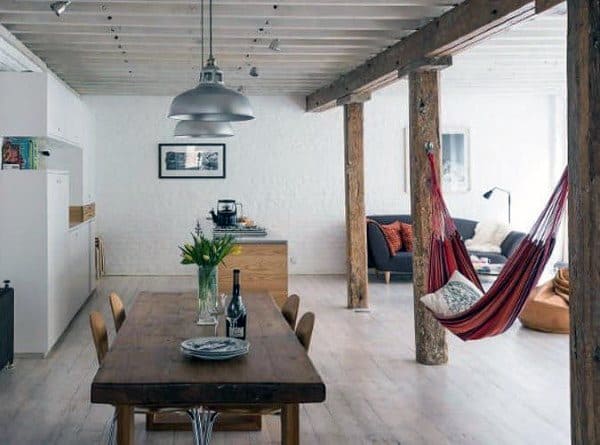 Red hammock in a modern dining and living space with wooden beams and cozy decor.