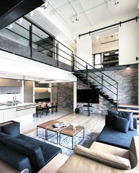 Modern loft with open layout, brick accent wall, metal staircase, and contemporary furniture.