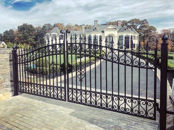Ornate wrought iron driveway gate with scrolling details and spiked finials.