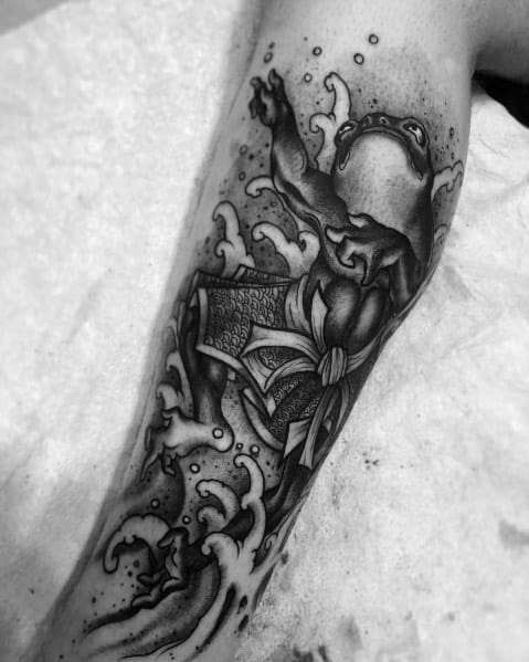 Black and grey Japanese-style tattoo featuring a warrior frog in traditional armor, leaping through crashing waves, symbolizing strength and resilience.