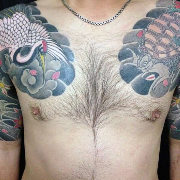 Japanese-style chest and shoulder tattoos featuring a turtle, a crane, and flowing waves with floral accents, symbolizing longevity and harmony.