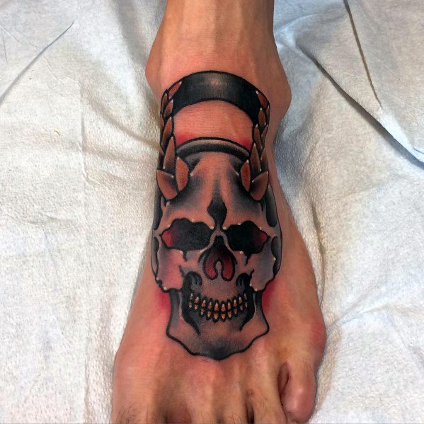 Bold kettlebell skull tattoo on the foot with dark shading and red accents, symbolizing strength, resilience, and an intense dedication to fitness.