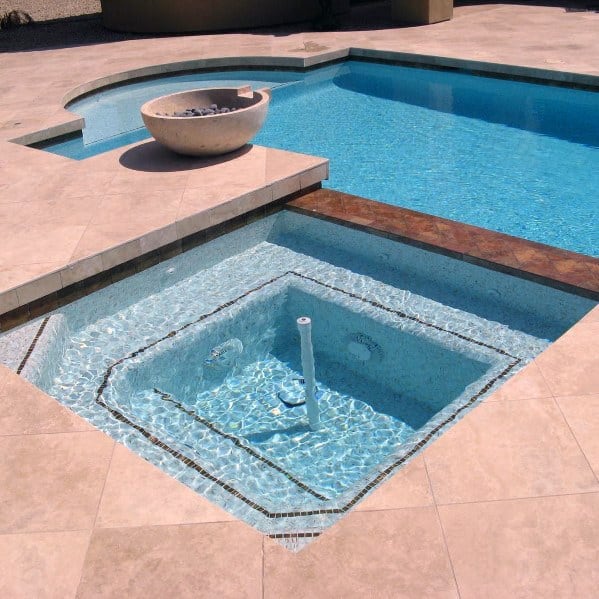 Luxurious pool featuring a limestone deck with a built-in hot tub adorned with intricate tile borders for a refined look.