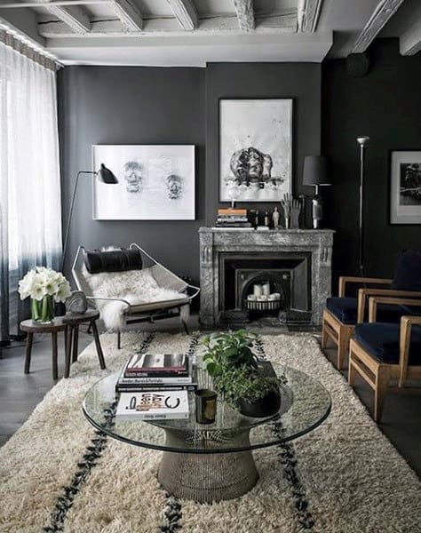 Contemporary living room with dark walls, marble fireplace, and glass coffee table.