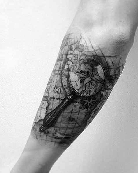 Tattoo of a magnifying glass focusing on a vintage world map, designed with intricate shading and fine details for a bold and exploration-themed look.