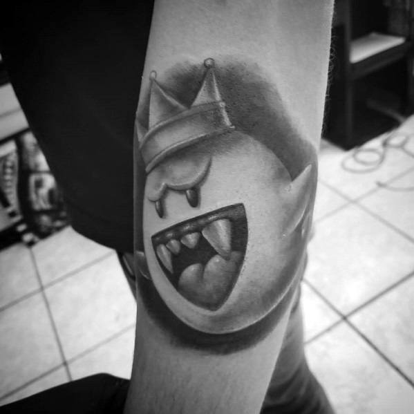 Realistic black and grey Mario ghost tattoo featuring King Boo with a crown, fierce expression, and smooth shading, inked on the forearm.