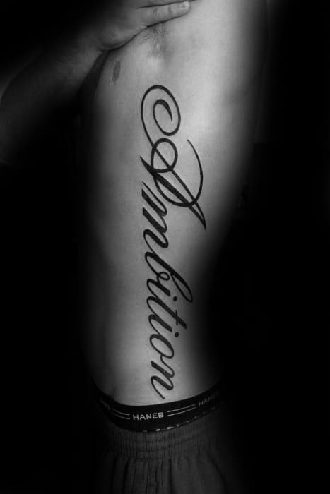 Cursive "Ambition" tattoo graces a side, set against a strikingly dark background
