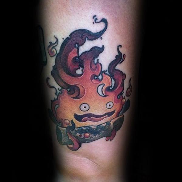 Stylized Calcifer tattoo with swirling, smoky flames, a surprised face, and dark logs accented with green and purple tones.