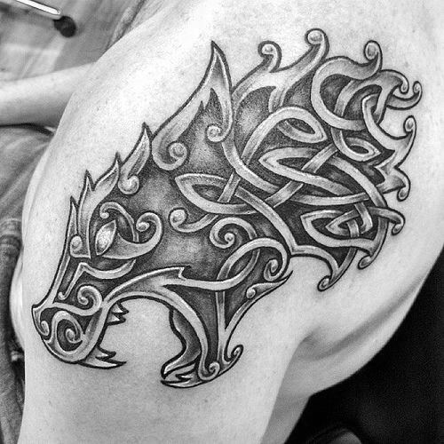 Celtic wolf head tattoo on shoulder with swirling knotwork and pointed accents forming a fierce, stylized silhouette.
