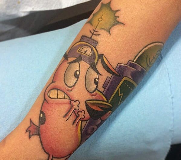 Colorful Courage the Cowardly Dog tattoo showing him looking scared with wide eyes, surrounded by abstract buildings and lightning on the forearm.