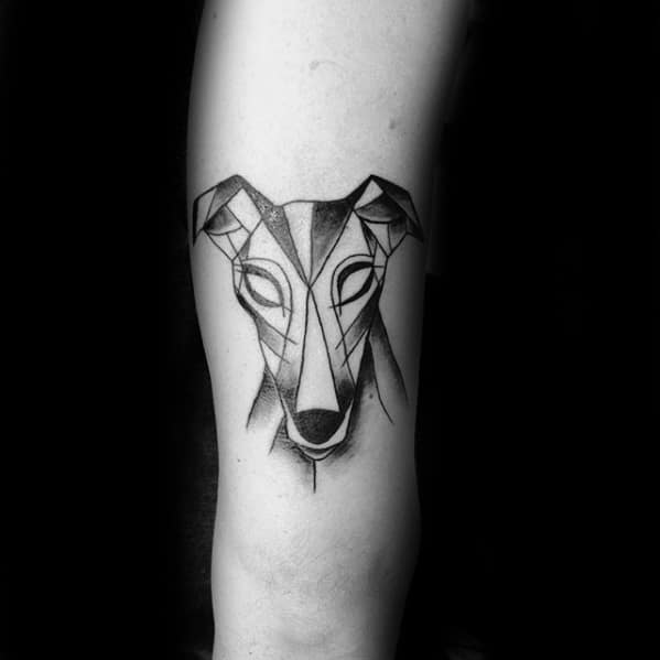 A geometric-style tattoo of a greyhound’s face, with bold lines and triangular shapes creating a modern and artistic interpretation of the dog's features.