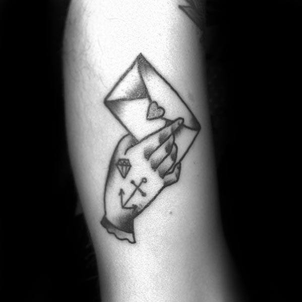 Tattoo of a hand with a heart holding an envelope stamped with love