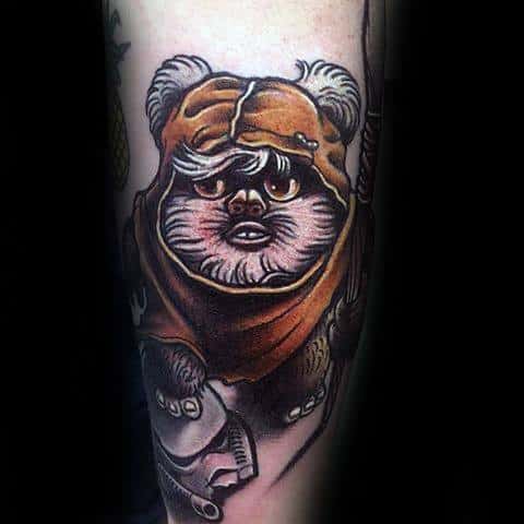 Bold Ewok tattoo with an orange hood and intense eyes, standing over a Stormtrooper helmet in a stylized illustrative design.