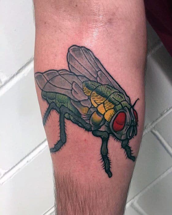 Bold and colorful fly tattoo on the calf with vibrant green, yellow, and red shading, featuring detailed wings and thick outlines.