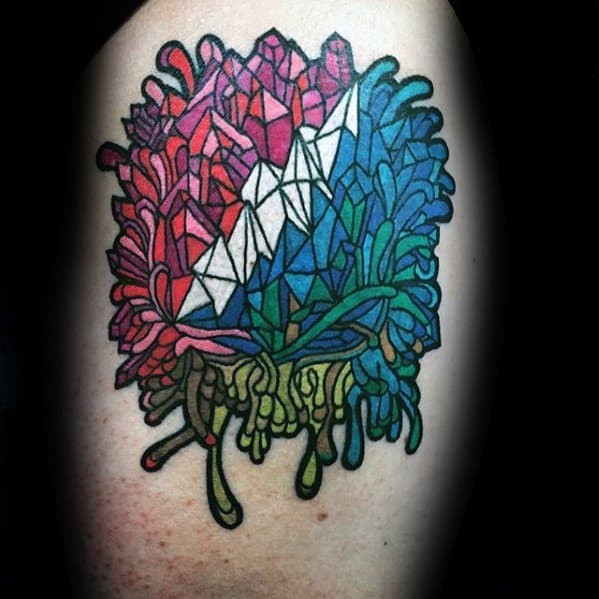 Grateful Dead tattoo with geometric crystals in red, white, and blue, blending into dripping green psychedelic shapes.