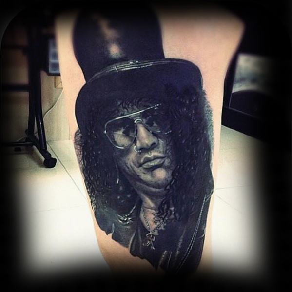 Hyper-realistic black and grey tattoo of Slash wearing a top hat, sunglasses, and curly hair, capturing his iconic Guns N' Roses look.