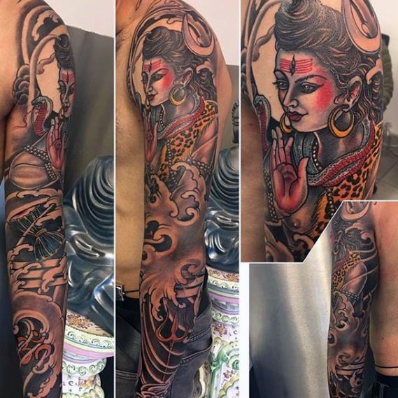 Vibrant full-sleeve tattoo of Lord Shiva with red facial highlights, crescent moon, cobra, and trident, surrounded by dynamic water and wave motifs.