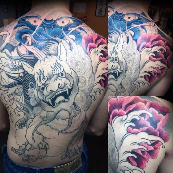 Full-back Kirin tattoo in progress with a bold, expressive face, swirling clouds, deep blue and pink accents, and emerging floral elements.