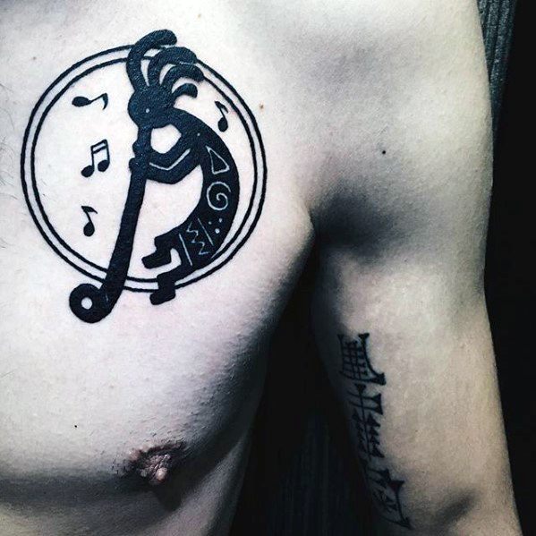 Bold black Kokopelli tattoo with musical notes and geometric patterns inside a circular frame, emphasizing the figure's fluid motion and connection to music.